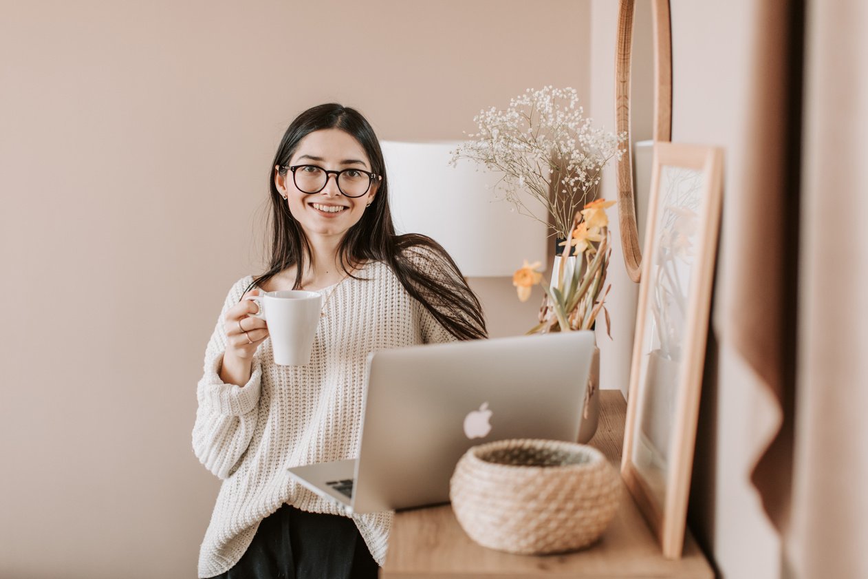 Woman Standing With A Cup Of Coffee Near A Laptop